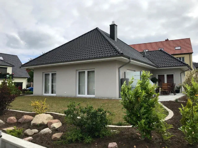 Verputzter Bungalow mit Walmdach und angelegtem Garten