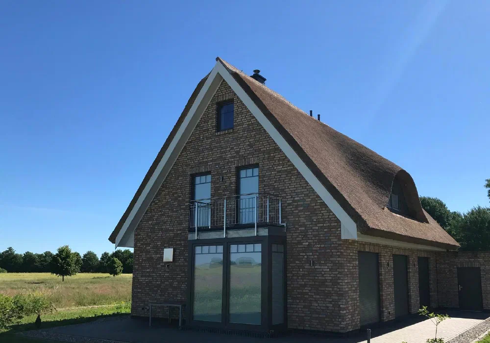 Einfamilienhaus aus Klinker mit Reetdach und raumhoher Glasfront